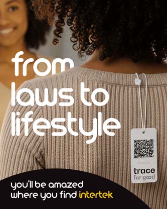 A woman smiling into a mirror while wearing a sweater with the price tag clipped to the back